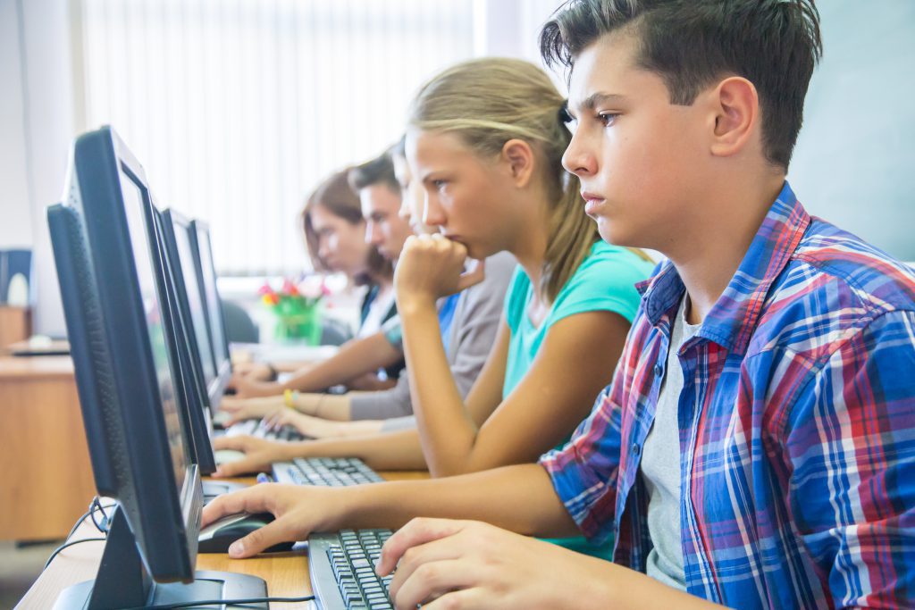 Młodzież szkolna w klasie pracuje przy komputerach
